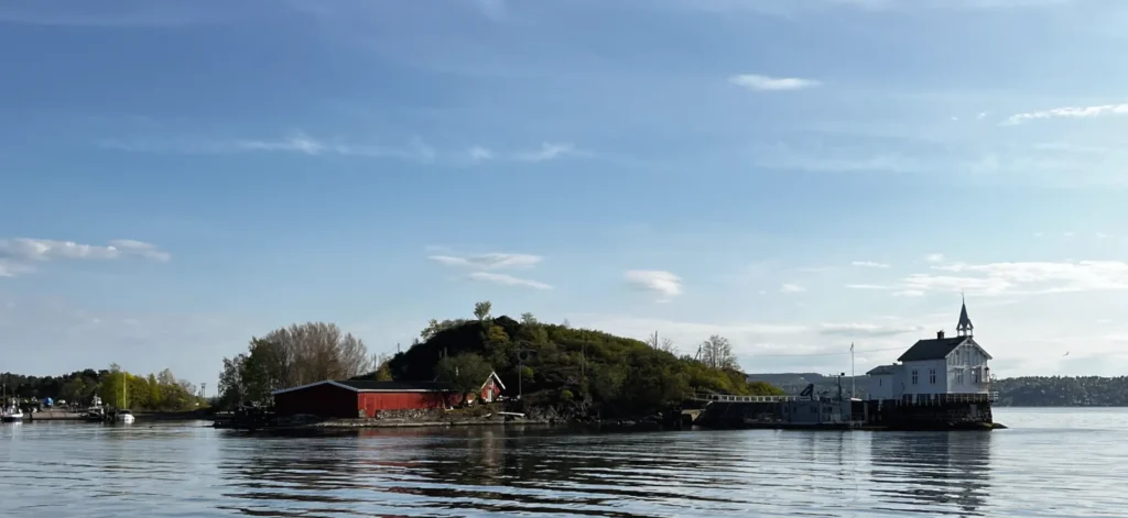 Im Vordergrund Wasser mit einem Gebäude und Hügel.