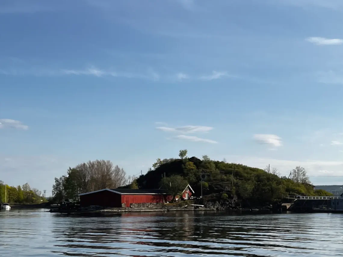 Im Vordergrund Wasser mit einem Gebäude und Hügel. Oslo Sehenswürdigkeiten
