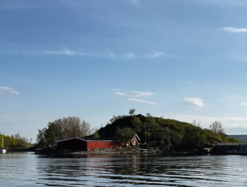 Im Vordergrund Wasser mit einem Gebäude und Hügel. Oslo Sehenswürdigkeiten