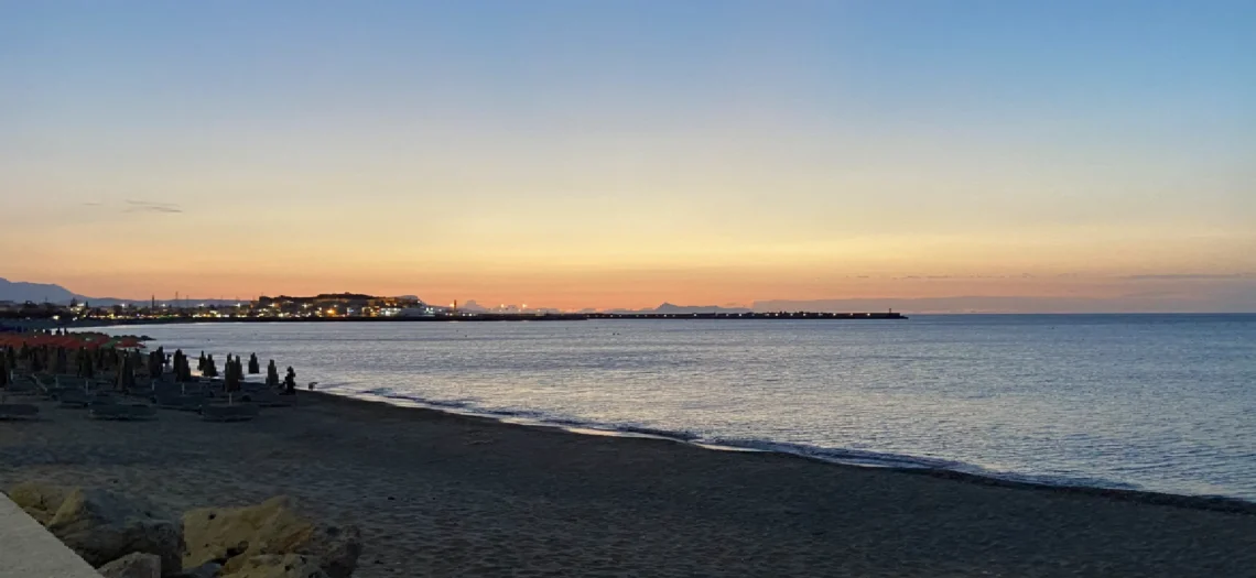 Strand mit einem Hafen im Hintergrund.