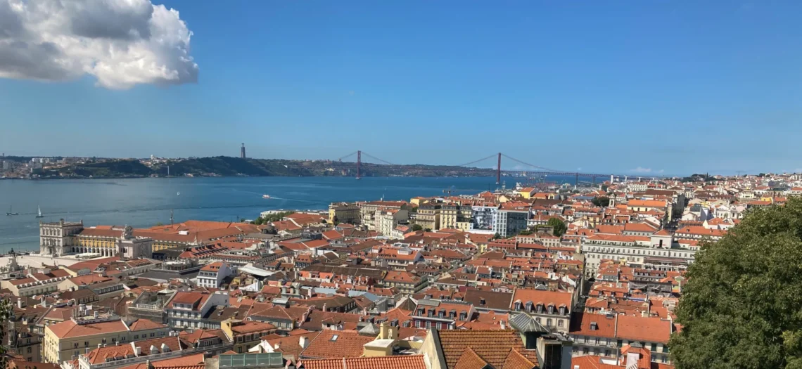 Eine Stadt mit roten Dächern und eine Brücke die über das Wasser führt.