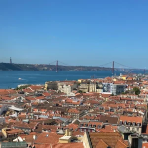 Eine Stadt mit roten Dächern und eine Brücke die über das Wasser führt.